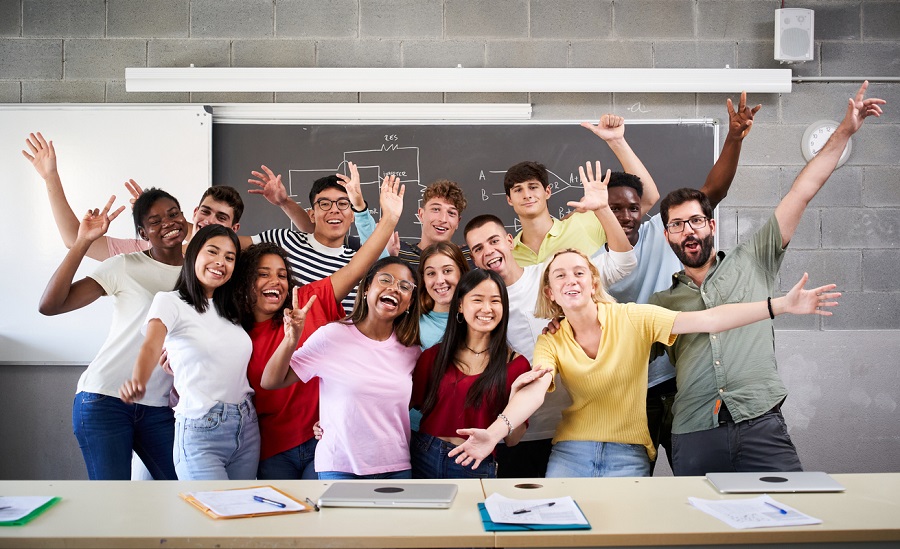 Portrait of a cheerful group of students celebrating in class