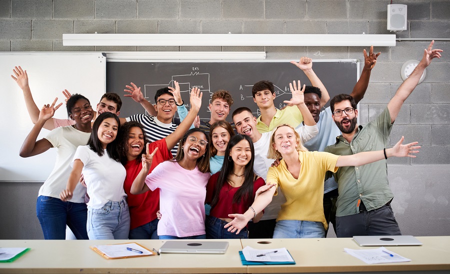 Portrait of a cheerful group of students celebrating in class 