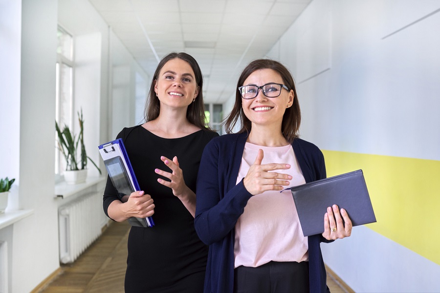 Two colleagues of teachers walking and talking 